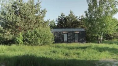 Sabah ormanında küçük bir kulübe, yeşil çimenler, ağaçların tepesinde güneş ışığı. Konforlu ahşap ev, ağır çekim. Yüksek kalite 4k görüntü