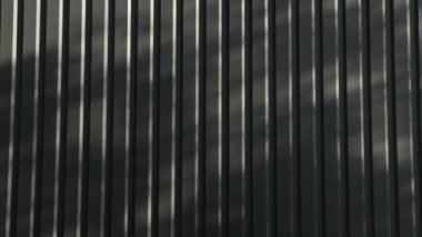 Açık havada çekilen metal duvar kamerası, yazın yeşil ormandaki küçük evin üzerindeki ağaçların gölgesi, güneş ışığı lekeleri, evin siyah metal yapısı, yavaş çekim. 4k 