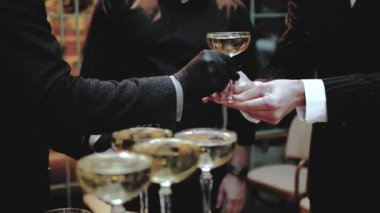 Yakından gelen siyah eldivenli garson bir restoran misafiri için kuleden bir kadeh şampanya kaldırıyor, düğün, şampanyalı garsonun yakın çekimi, siyah takım elbiseli adam, yavaş çekim. 4k
