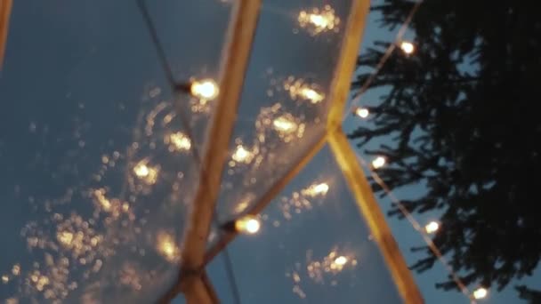 バーティカルビデオ 明るい電球は透明なテントの天井からぶら下がるガーランド 夜の屋外の照らされたガーランドを ゆっくり動かします 高品質の映像 — ストック動画