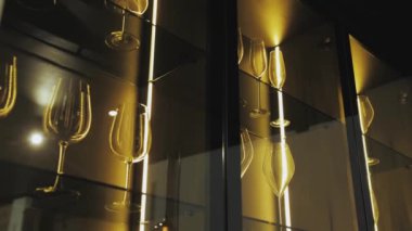 Bir sıra şarap kadehi cam bir rafta mükemmel bir şekilde dizilmiş, görsel olarak hoş bir görüntü yaratıyor. Zarif ve sofistike bir ortam lüks bir hayat tarzı sergilemek için idealdir. 