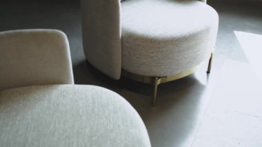 Kollukları olan iki beyaz sandalye, şık bir otomotiv tasarımını andıran fayanslı ve beton döşemeli odada rahatlık ve samimiyet hissi yaratıyor.