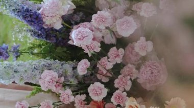 Gelin ve damat masasının yanında taze çiçeklerle süslenmiş güzel bir düğün süsü turuncu, pembe, mor renkler, düğün için taze çiçek aranjmanları. Dikey video