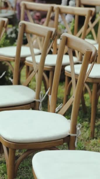 前面可以看到许多木制的椅子 上面有白色的枕头和美丽的花卉风格的构图 婚礼在外面的树林中举行 动作缓慢 是的高质量的4K镜头 — 图库视频影像