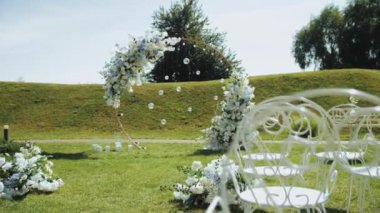 Gökyüzünün altındaki çimenlik alana ve bir düğün töreni için bir ağacın yanına bir sıra sandalye konur. Karasal bitkiler ve otlaklarla çevrili.