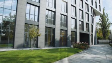 Geniş pencereli, yemyeşil manzaralı çağdaş bir ofis binası. Gösterişli tasarım ve geniş ön çimler şehir tasarımında göze çarpıyor.