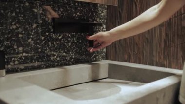Bir kadının eli banyoda siyah bir musluğu çevirir. Su akıyor. Karanlık banyo, siyah musluk ve mermer lavabo, yavaş çekim. Yüksek kalite 4k görüntü