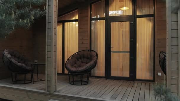 房子的门廊上有两把硬木椅子 挨着木门和窗户 门廊用的建筑材料是复合材料 地板是用硬木做的 — 图库视频影像