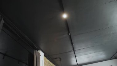 Bir projektör tavan arasındaki karanlık odayı aydınlatıyor. Gece yarısı sokak lambasına benzer bir ışık sağlıyor.