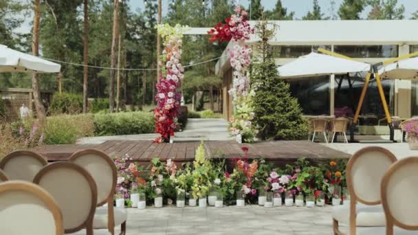 緑豊かな花と魅力的な花の装飾の背景に設定された素敵な屋外の結婚式 椅子のローズは美しく装飾されたアーチに直面し 組合のためのロマンチックな雰囲気を作成します — ストック動画