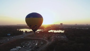 Gün batımında gökyüzünde yüzen sıcak hava balonunun büyüleyici görüntüsü çarpıcı bir doğal manzara ve ufuk manzarası sergiliyor.