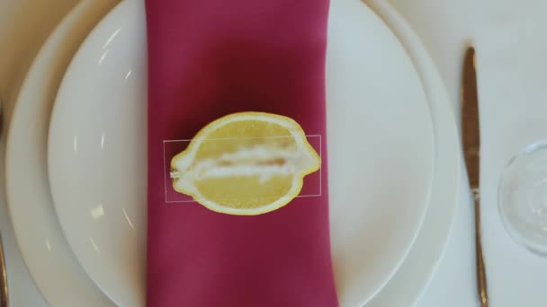 レモンスライスは さまざまな色合いと色合いのテーブルウェアでフレームされたプレート上のナプキンに座り クローズアップスローモーションショット — ストック動画