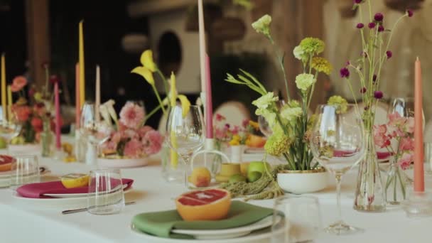 プレート ろうそく 果物とエレガントに設定されたテーブルは 特別なイベントのための植物の配置や皿の美しい表示を作成します — ストック動画