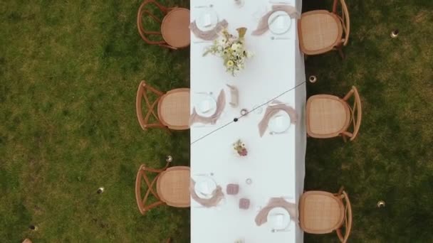 緑の芝生の外に位置するお祝いのテーブルと木製の椅子の空中ビュー 結婚式のトップテーブルからのクローズアップビュー 結婚式 高品質の4K映像 バーティカルビデオ — ストック動画