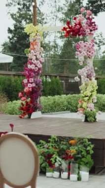 Düğün kemeri. Çiçeklerle süslenmiş ve sandalyelerle çevrili büyüleyici ahşap bir sahne düğün törenini bekliyor. Sandalyeler ön tarafa düzgünce dizilmiştir. Yakın plan. Dikey video