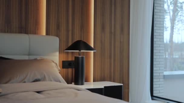 一间舒适的卧室 有硬木地板和木家具 包括床 床头柜和灯 有窗帘的窗户增添了自然光和室内设计的色彩 — 图库视频影像