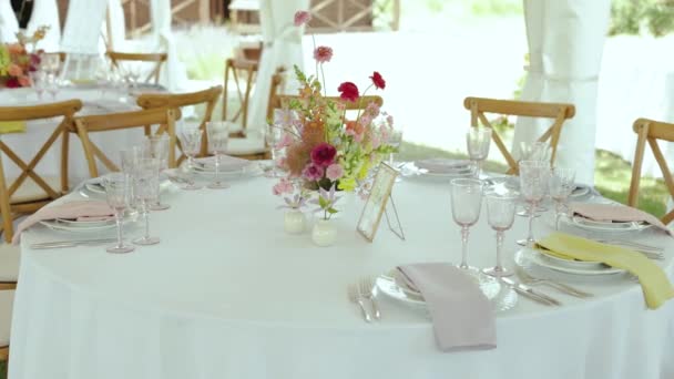 漂亮的餐具 鲜花和植物摆设精美的餐桌 放在一个帐篷下举行婚宴 家具和酒具完成了令人惊叹的室内设计 — 图库视频影像