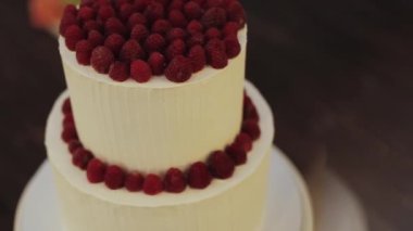 Masanın üzerinde taze ahududular sergilenen güzel dekore edilmiş bir düğün pastası. Pasta, her özel gün için nefis bir süs eşyası.