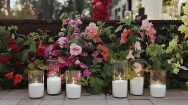 Düğünden önce bir grup mum bir düğünde yerde duruyor. Pembe yapraklar güzel bir çiçek aranjmanı oluşturuyor.