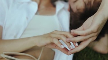 Huzurlu bir an, birbirine dolanmış elleri gösteriyor, doğal ortamdaki bağları ve yakınlığı sembolize ediyor..
