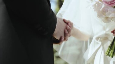 Birbirlerine sarılmış çiftlerin elleri, düğün günlerinde birbirlerine olan derin sevgilerini ve bağlılıklarını simgeler.