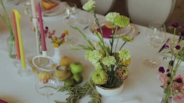 Çok güzel düzenlenmiş bir yemek masası. Canlı çiçekler, taze meyveler ve davetkar bir hava için titreyen mumlar.