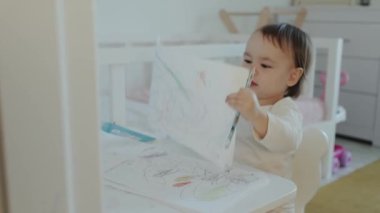 Genç bir çocuk, neşeli bir ortam yaratan rahat ve aydınlık bir oyun odasını neşeyle boyuyor.