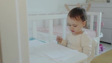 Hoş ve tapılası bir çocuk, rahat bir kreş ortamında çeşitli sanatsal aktivitelere odaklanıyor.