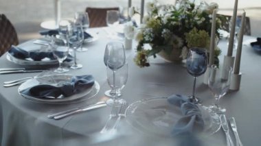 Güzel düzenlenmiş yemek masası göz kamaştırıcı mavi elementler, zarif cam eşyalar ve canlı taze çiçekler.