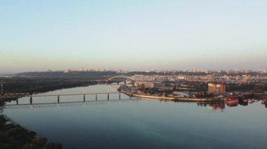 Hava görüntüsü, canlı bir şehir nehri ve sıcak sabah ışığını güzel yansıtan bir köprüyü gösteriyor.