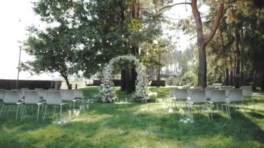 Zarif bir açık hava düğün töreni çiçek süslemeleri ve doğada büyüleyici sandalyelerle süslenmiş.