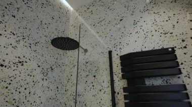 Bu çağdaş duş modern bir dokunuş için parlak, şık siyah armatürlerle donatılmış terrazzo duvarlarıyla övünür.