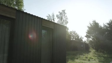 Büyüleyici ve parlak yeşil bir kulübe, doğanın içine güzelce yerleştirilmiş, sabah güneşiyle hafifçe aydınlatılmış.