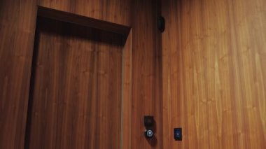 Asansör kapısı güzel bir ahşap iç mekâna kurulmuş. Dokunma düğmesi kontrollü parlak bir tasarım sergiliyor.