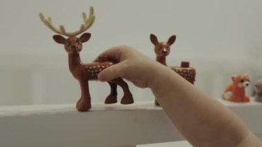 Bir çocuk parlak figürler arasında renkli bir oyuncak atı tutarak yaratıcı oyun ve yaratıcılığı teşvik eder.