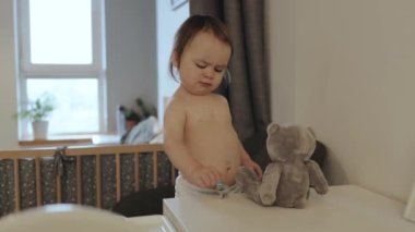 Sevimli küçük bir çocuk, rahat bir oyuncak ayıyla güzel bir oyun anının tadını çıkarıyor.