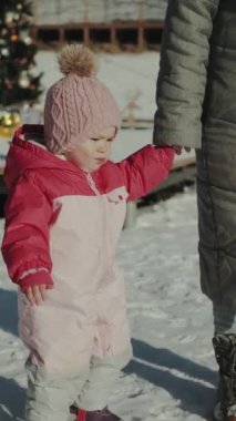 Renkli kış kıyafetleri içinde genç bir çocuk karda neşeyle yürüyor, saf neşe ve masumiyet saçıyor. Dikey video