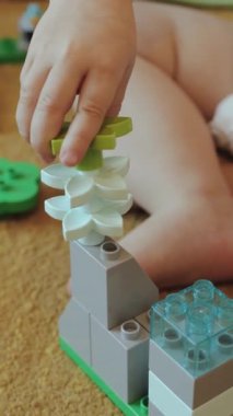 Bir çocuk eğlenceli bir şekilde renkli bloklarla oynar, oyun sırasında yaratıcılığı ve iyi motor becerileri artırır. Dikey video