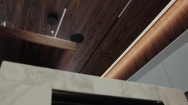 Bu şık ve modern iç mekan, yumuşak ortam ışıklarının yanı sıra çeşitli ahşap dokuları da sergiliyor.