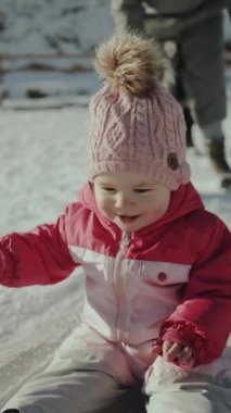 Neşeli ve mutlu bir çocuk, eğlenceli pembe bir kıyafet ve rahat bir şapka içinde karın tadını çıkararak harika vakit geçiriyor. Dikey video