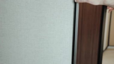 Modern ve çağdaş ofis ortamında kumaş bir bölmeyi tutan bir elin detaylı yakın plan görüntüsü.