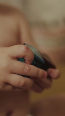 Dikey video, genç bir çocuğun canlı, renkli bir bulmaca küpünü ustalıkla manipüle ettiği detaylı bir yakın çekim.