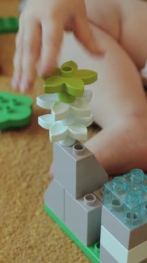 Dikey video. Yaratıcılığı ve canlılığı teşvik eden renkli yapı taşlarını hevesle istifleyen küçük bir çocuk.