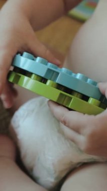 Dikey video. Neşeli bir çocuk renkli oyuncaklarla oynar, yaratıcılığı arttırır ve motor becerilerini geliştirir.