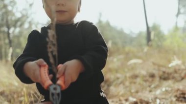 Küçük bir çocuk doğayla neşe içinde etkileşime girer, bahçeyle ilgili aletleri kullanarak dışarıda keşfe çıkar.