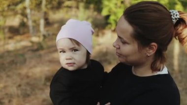 Bir annenin çocuğunu sevgi dolu bir şekilde dışarıda, huzurlu ve doğal bir ortamda tutmasının şefkatli ve iç açıcı bir anı.