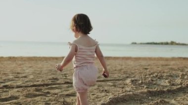 Neşeli bir çocuk mutlu bir şekilde köpüklü suya yakın kumlu sahilleri keşfeder, doğayı ve eğlenceli eğlenceleri kucaklar.