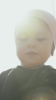Neşeli bir şapka takan, masumiyeti ve sıcaklığı sembolize eden, gün ışığında bir çocuğun yürek ısıtan bir fotoğrafı. Dikey video. 