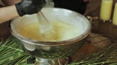 Yetenekli bir barmen, taze otlarla çevrili parlak gümüş bir kasede kremalı ve lezzetli bir içeceği ustalıkla karıştırır.