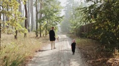 Sevgi dolu bir bakıcı ve neşeli bir çocukla huzurlu bir orman yolunda birlikte yürüdüğümüz huzurlu bir an.